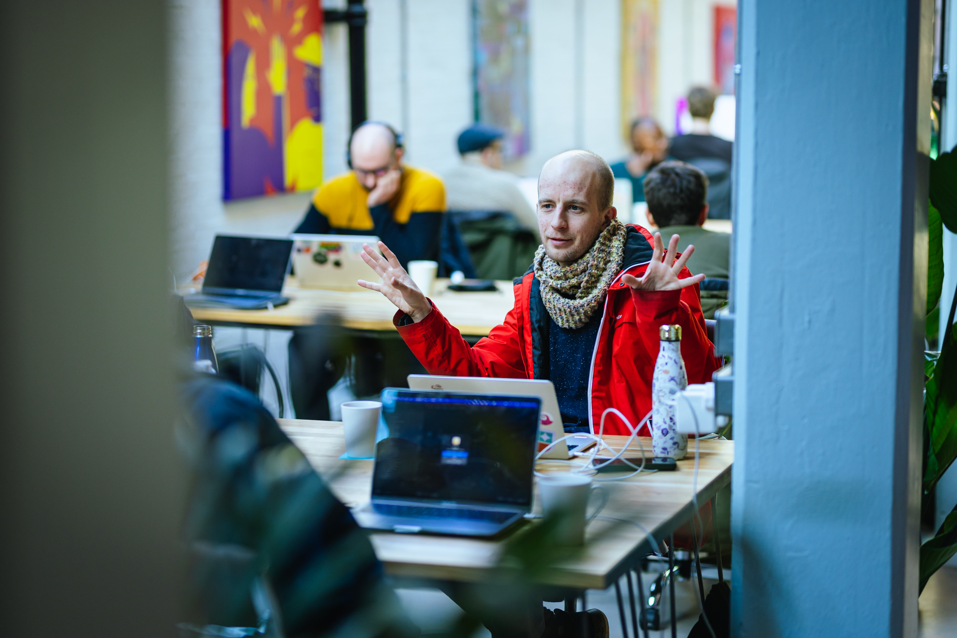 A male member of the Substrakt team seated at a table raises his hands, expressing surprise or excitement in a candid moment.