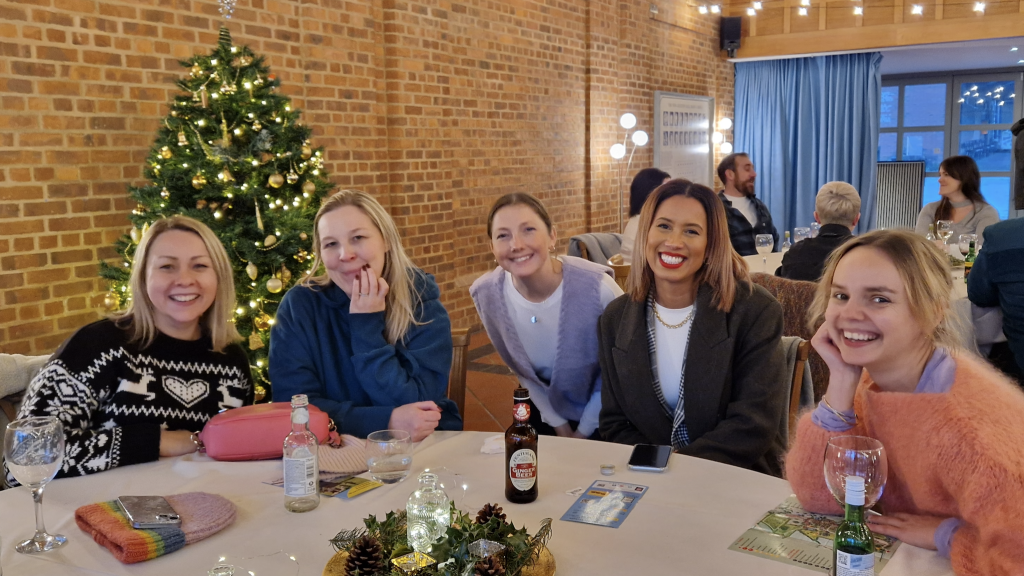 A group of five women at Substrakt sat at a table, smiling.